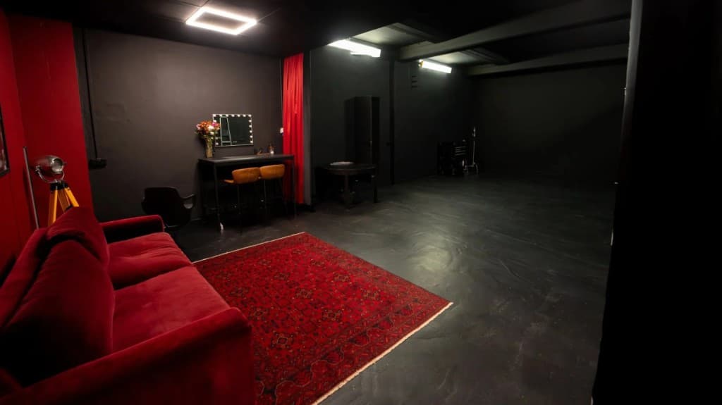 STU22 - black floor studio with red sofa, rug, and open shooting space
